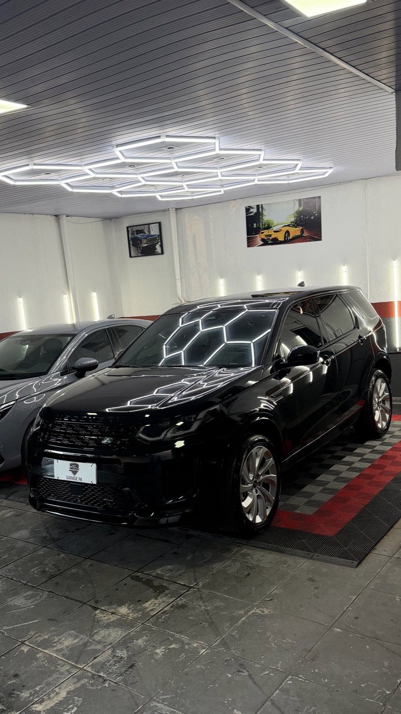 Carro preto refletindo a iluminação da cabine da Garage FK
